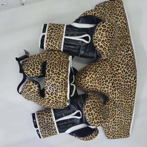 Puede incluir: Un conjunto de equipamiento de boxeo con estampado de leopardo. El conjunto incluye guantes de boxeo, protector de cabeza y protector corporal. Los guantes tienen detalles en cuero negro y ribete blanco.