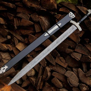 May include: A double-edged sword with a patterned Damascus steel blade, a black handle, and a silver-toned crossguard and pommel. The sword is accompanied by a black scabbard featuring silver-toned metal accents at the tip and throat.