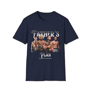 Puede incluir: Camiseta azul marino con un gráfico de cuatro hombres con guantes de boxeo y cinturones de campeonato. El texto "Father's Plan" está impreso en plata debajo del gráfico.