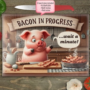 May include: A glass cutting board with a cartoon pig and the text "BACON IN PROGRESS... wait a minute!" The pig is pink and has a surprised expression. The cutting board is brown and has a rustic look.
