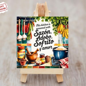 May include: Watercolor illustration of a kitchen scene with cooking ingredients. The image features text that reads "This kitchen is seasoned with Sazón, Adobo, Sofrito y amor." Includes garlic, peppers, bananas, and a pot of rice.