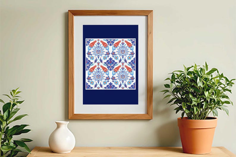 May include: A framed print featuring a detailed floral pattern in shades of blue, red, and white. The artwork is set against a dark blue background and framed in a light brown wooden frame. The print is displayed on a wooden surface.
