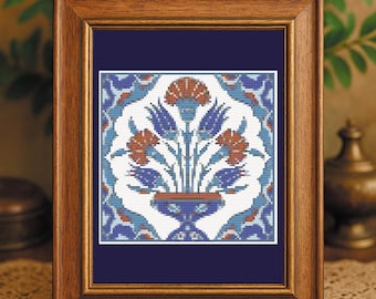 May include: A framed artwork featuring a floral design in a vase. The artwork has a white background with blue, orange, and red floral elements. The frame is made of wood and is displayed on a wooden surface.