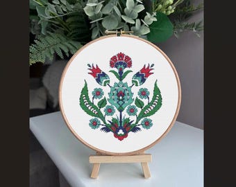 May include: A cross-stitch embroidery hoop with a floral design. The design features red, blue, and green flowers on a white background.