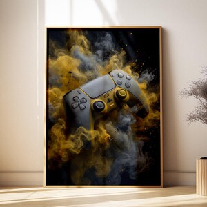 May include: Framed artwork featuring a gray and gold video game controller set against a backdrop of swirling yellow and gray smoke. The controller has a modern design with multiple buttons and joysticks, creating a dynamic and visually striking composition.