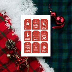 May include: Printable gift tags with a red background and white text. The tags feature various holiday greetings, including "Merry Christmas", "Happy Holidays", and "Special Delivery".