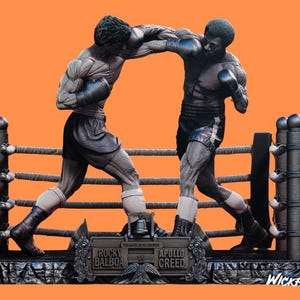 May include: A black and white boxing statue featuring two figures in a fighting pose. The statue is set against a boxing ring with ropes and posts. The base of the statue features the names "Rocky Balboa" and "Apollo Creed".