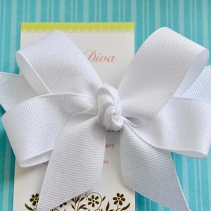 May include: A white bow with a sparkly finish, tied on a card with the word "Diva" printed on it.