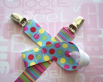 May include: Two colorful ribbon pacifier clips with silver metal clips. One ribbon is blue with pink, yellow, and green polka dots. The other ribbon is blue with pink, yellow, and green stripes.
