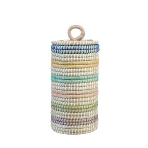Peut inclure: Un panier cylindrique tressé avec un couvercle et une poignée. Le panier est fait de fibres naturelles et présente des rayures horizontales de différentes couleurs, dont le bleu, le jaune, le vert et le violet. Le couvercle a une poignée circulaire.