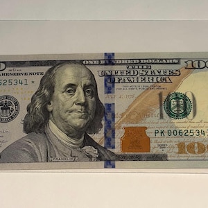 May include: A United States one hundred dollar bill, featuring a portrait of Benjamin Franklin. The bill is green and black, with the text "FEDERAL RESERVE NOTE" and "ONE HUNDRED DOLLARS". The serial number is PK 00625341*.