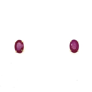May include: A pair of oval-shaped ruby earrings set in gold.