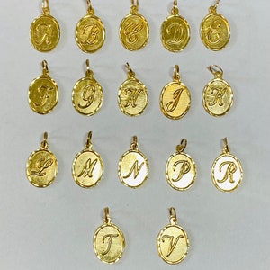Puede incluir: Un conjunto de 18 colgantes de color dorado, cada uno con una letra diferente del alfabeto. Los colgantes son de forma ovalada y tienen un borde ligeramente elevado.