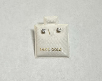 May include: A pair of small diamond earrings on a white card with the text "14KT GOLD".