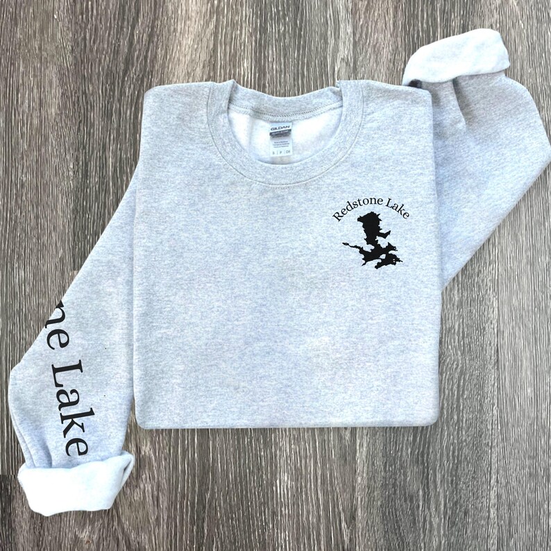 May include: A gray sweatshirt with the text "Redstone Lake" and a black outline of a lake on the front. The left sleeve has the text "Stone Lake" printed on it.