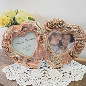 Peut inclure: Deux cadres photo en forme de cœur avec des détails de roses et de tulipes. L'un des cadres porte l'inscription "Flower Garden From The Heart". L'autre cadre contient une photo de 12,7x12,7 cm. Les cadres sont de couleur cuivre.
