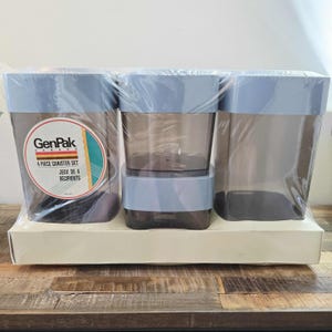 Peut inclure: Un ensemble de 4 boîtes de conserve GenPak Canada. L'ensemble comprend quatre boîtes rectangulaires transparentes avec des couvercles bleu clair, emballées dans du plastique transparent. Le logo GenPak et les détails du produit sont visibles.