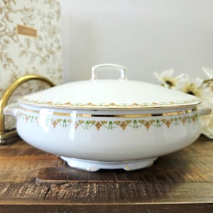 May include: A white ceramic mug with a black handle and the text "But First, Coffee" in a black, bold font. The mug is on a white surface.