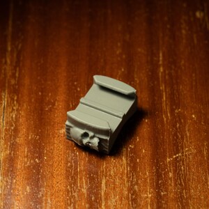 May include: A gray plastic camera mount with a skull-shaped design.