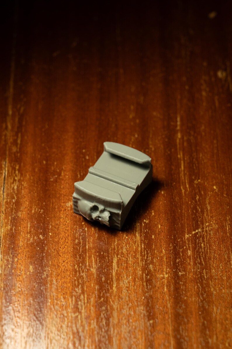 May include: A gray plastic camera mount with a skull-shaped design.