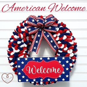 May include: A red, white, and blue yarn wreath with a red, white, and blue bow and a sign that says "Welcome" in red letters on a blue background with white stars.