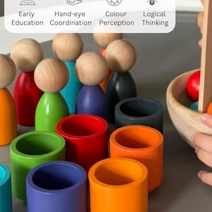 Peut inclure: Un ensemble de jouets en bois avec des personnages en bois colorés et des tasses, ainsi qu'un bol en bois et des pinces. L'ensemble est conçu pour aider les enfants à développer leur coordination œil-main, leur perception des couleurs et leurs capacités de réflexion logique.