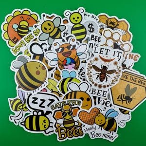 May include: A collection of colorful bee-themed stickers with various designs and sayings, including "Don't Bee Sa", "We Die", "Bee Nice", "Let It Bee", "Save The Bees", "Honey Bee Mine", and "ZZZ".
