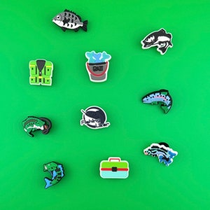 Puede incluir: Nueve abalorios de zapatos coloridos con temas de pesca. Los abalorios incluyen un cubo de pesca, un chaleco salvavidas, un pez y un señuelo de pesca. Los abalorios están hechos de goma y tienen un acabado brillante.