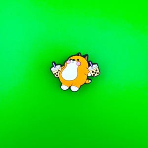 May include: A cartoon orange and brown fox holding two cups of boba tea with purple straws. The fox is smiling and has pink cheeks. The background is a solid green.