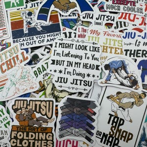 May include: A collection of colorful stickers featuring various designs related to jiu-jitsu. The stickers include phrases like "Jiu-Jitsu and Chill", "The Art of Folding Clothes", and "Jiu-Jitsu is my Therapy".
