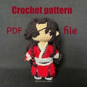 May include: A handmade crochet doll in a red and white outfit, with long black hair and an eye patch. The doll is a PDF crochet pattern file. The text "Crochet pattern PDF file" is displayed in red.