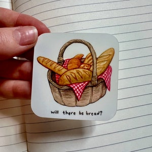 May include: A white sticker with a cartoon illustration of a wicker basket filled with various loaves of bread. The text "will there be bread?" is printed below the basket.