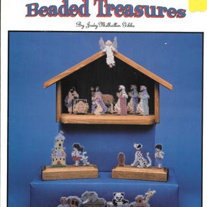 May include: A book cover for a beaded craft project titled "Beaded Treasures" by Judy Milhollin Gibbs. The cover features a nativity scene, a train, and a dog.
