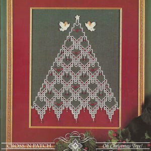 May include: Framed cross-stitch pattern featuring a Christmas tree design. The tree is white with red accents and is adorned with two angel figures at the top. The artwork is set against a green background within a red and gold frame. The text "Oh Christmas Tree!" is visible.