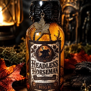 Pode incluir: Uma garrafa de vidro transparente com l&iacute;quido &acirc;mbar e elementos bot&acirc;nicos, selada com cera preta. Um pingente de folha de bordo de bronze pende do gargalo. O r&oacute;tulo diz Headless Horseman, Aspire Apothecary, Pocket Potion Series, Pursuit Risk High.