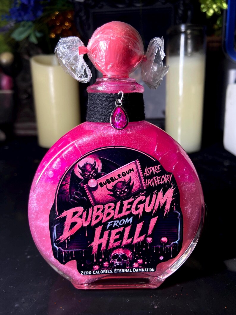 May include: A round glass bottle filled with shimmering pink liquid, topped with a pink candy-like sphere wrapped in clear plastic. A black fabric collar features a pink teardrop charm. The label reads BUBBLEGUM FROM HELL! ASPIRE APOTHECARY.