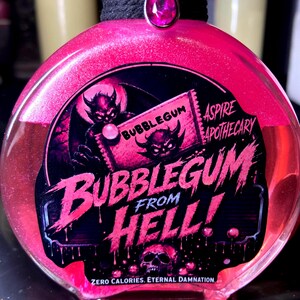 May include: A round glass bottle filled with shimmering pink liquid, featuring a black label with the text BUBBLEGUM FROM HELL, ASPIRE APOTHECARY, and ZERO CALORIES. ETERNAL DAMNATION. The bottle neck is wrapped in black cord with a pink teardrop charm.