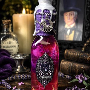 May include: A glass bottle filled with a vibrant pink liquid, featuring a label with a wolf illustration and the text "WOLFSBANE ELIXIR". The neck is wrapped in purple twine, adorned with a silver wolf charm, and topped with white wax.