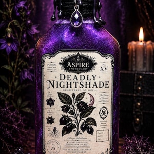 May include: A glass bottle filled with shimmering purple liquid, sealed with black wax and a purple crystal charm. The label reads ASPIRE APOTHECARY DEADLY NIGHTSHADE, featuring botanical illustrations of Atropa belladonna, a crescent moon, and a skull icon.