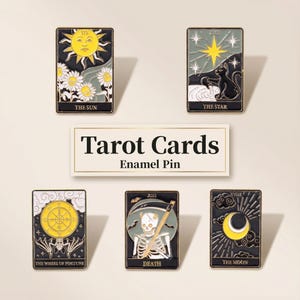 May include: A collection of enamel pins depicting tarot card designs. The pins showcase "The Sun," "The Star," "The Wheel of Fortune," "Death," and "The Moon." Each pin has a black border with gold detailing and intricate illustrations.