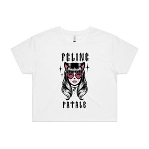 May include: White crop top with a graphic of a woman with cat ears and heart-shaped eyes. The text "FELINE FATALE" is printed above and below the illustration in a gothic font. The design is in black and pink.