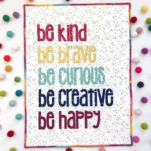 Pode incluir: Uma tapeçaria de parede acolchoada branca com um padrão de bolinhas pretas e o texto "be kind be brave be curious be creative be happy" em letras coloridas.