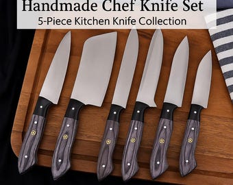 May include: A set of five handmade chef knives with black wooden handles and silver blades. The knives are arranged on a wooden cutting board. The text "Handmade Chef Knife Set 5-Piece Kitchen Knife Collection" is displayed above the knives.