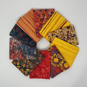 May include: A collection of colorful fabric squares arranged in a circular pattern. The fabrics feature various patterns, including floral, striped, and abstract designs in shades of red, yellow, blue, and orange. The squares are neatly folded.