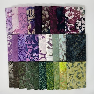 May include: A collection of fabric squares in various shades of purple, green, and yellow. The fabric features floral and abstract patterns. The squares are neatly stacked, showcasing a variety of designs and colors, perfect for quilting or crafting projects.
