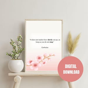 May include: A framed print with a quote by Confucius, featuring a soft pink and white gradient background with watercolor cherry blossoms. The text reads: "It does not matter how slowly you go, as long as you do not stop." A digital download is available.