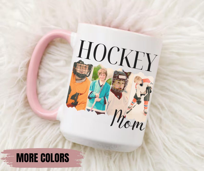 Puede incluir: Taza de cer&aacute;mica blanca con asa rosa. La taza presenta las palabras "HOCKEY Mom" en texto negro, junto con cuatro im&aacute;genes de jugadores de hockey. Las palabras "MORE COLORS" est&aacute;n en la parte inferior de la taza.
