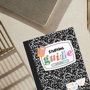 May include: Composition notebook with a black and white speckled pattern. The cover features the words "STUDYING guide" in colorful letters, with a small pink and yellow book graphic. A gold pen and laptop are in the background.