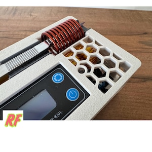 Könnte beinhalten: Nahaufnahme eines weißen Geräts mit einem schwarzen digitalen Display und zwei Knöpfen. Das Gerät hat eine Kupferspule und eine wabenförmige Lüftung. Der Text auf dem Display lautet "Y-WJ01".