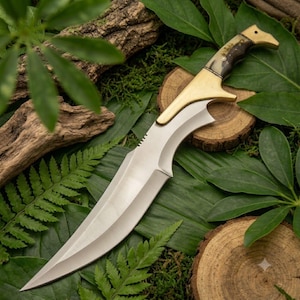 Peut inclure: Un couteau à lame fixe doté d'une lame en acier argenté incurvée et d'un manche avec une mitre en laiton poli et une poignée en corne sombre et texturée. Le couteau présente une pointe acérée et un dos incurvé avec une finition métallique.